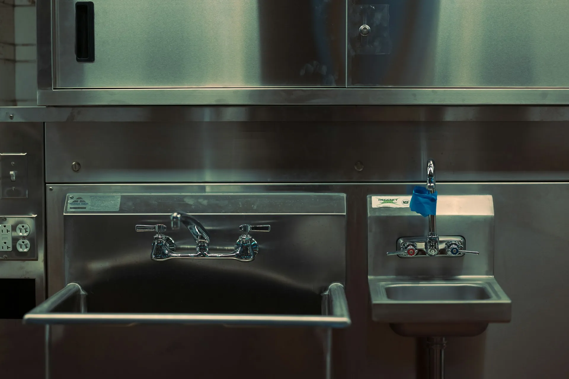 Dettaglio di una cucina professionale in acciaio inox: lavello e rubinetteria industriale.